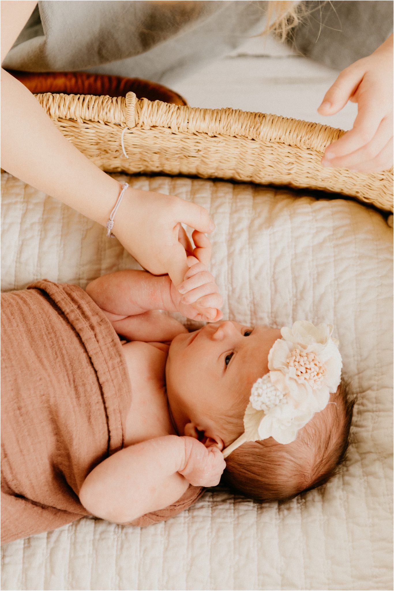 sister holding newborn baby sister hand