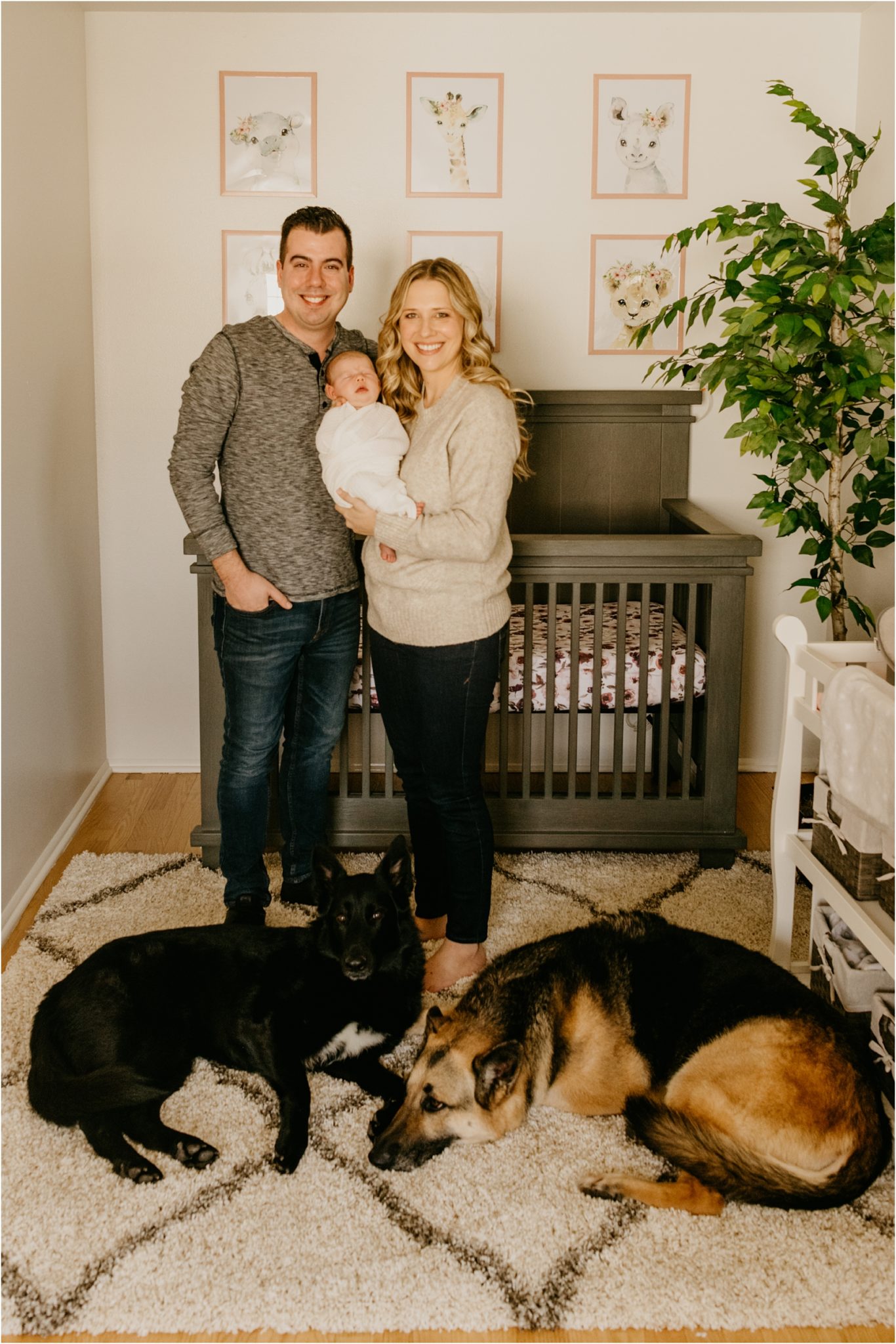 mom and dad holding baby with two dogs