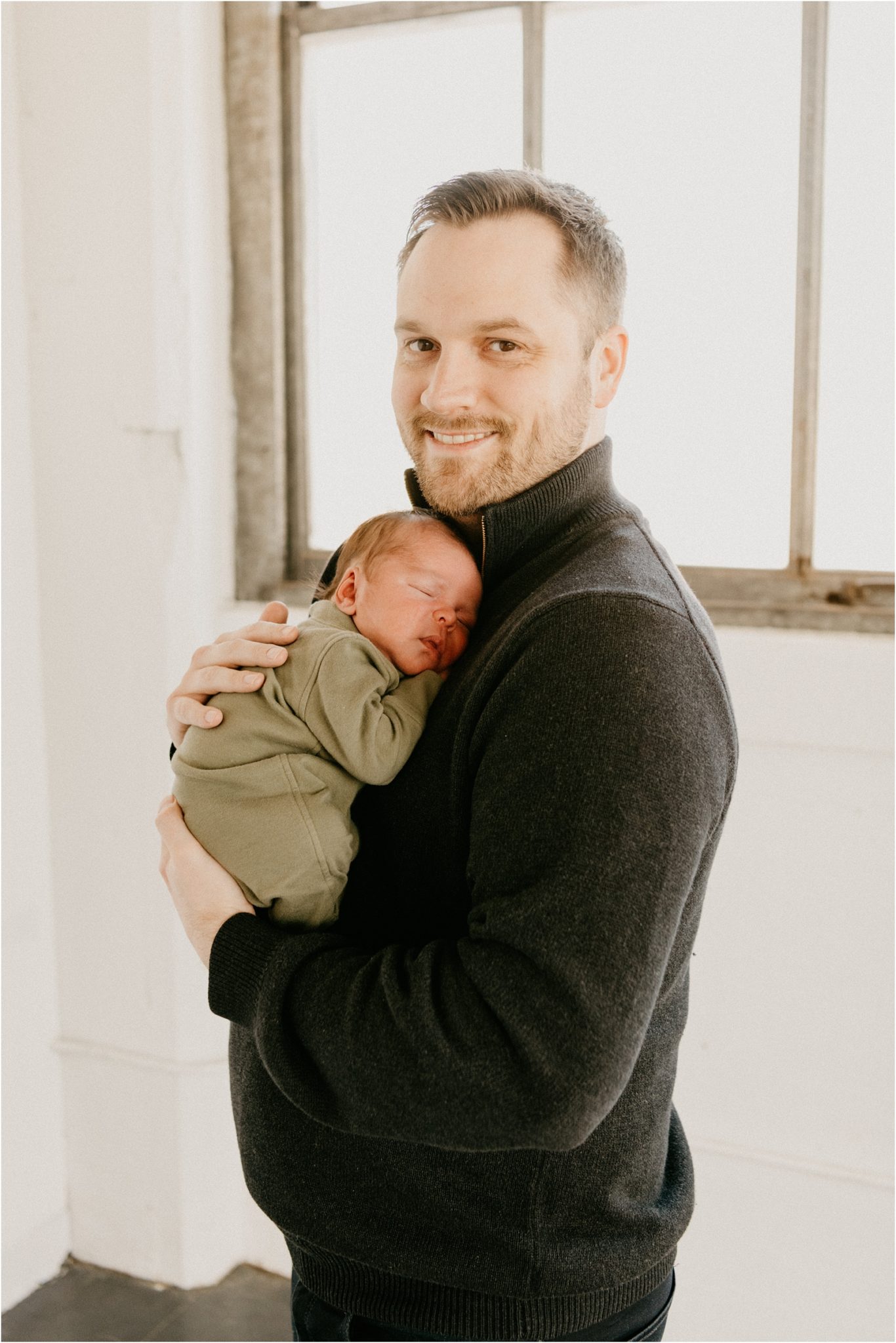 dad holding baby boy smiling at camera
