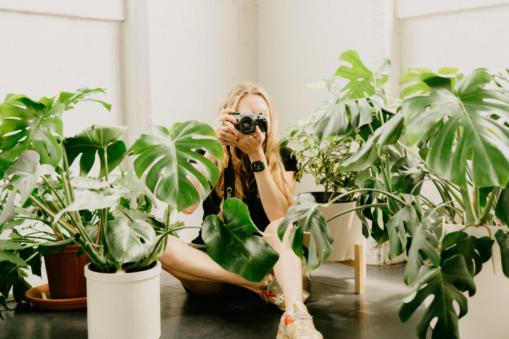 girl with camera surrounded by plants