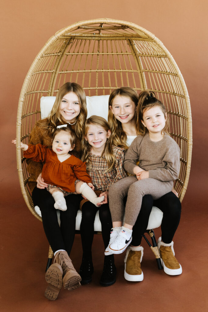 children in studio on brown backdrop in chair