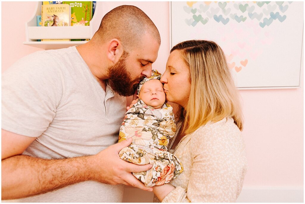 mom and dad holding baby kissing baby