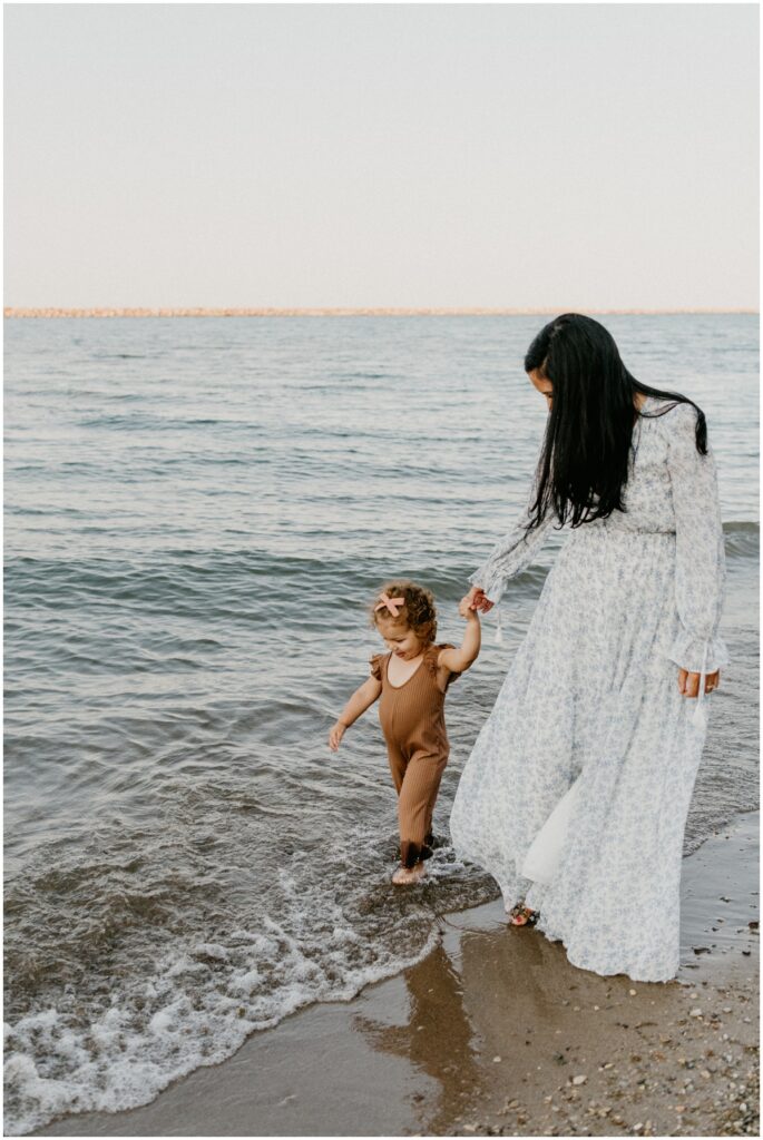 mom and daughter walking near water