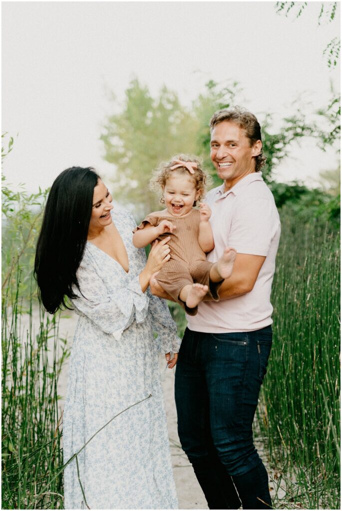 family holding little girl laughing