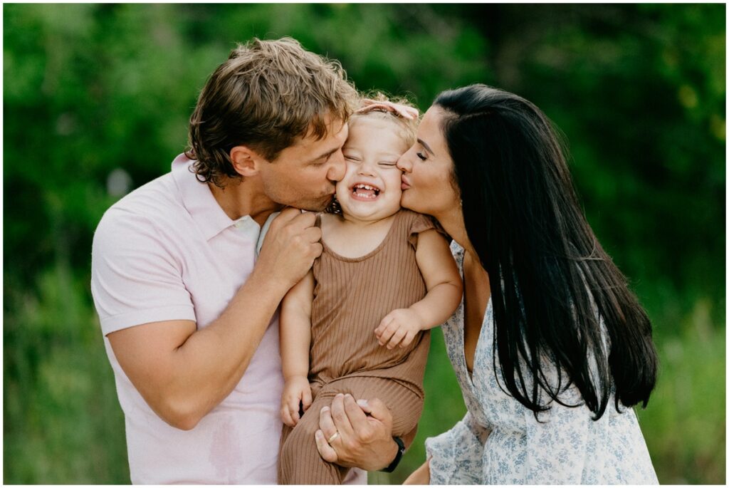 mom and dad kissing daughter