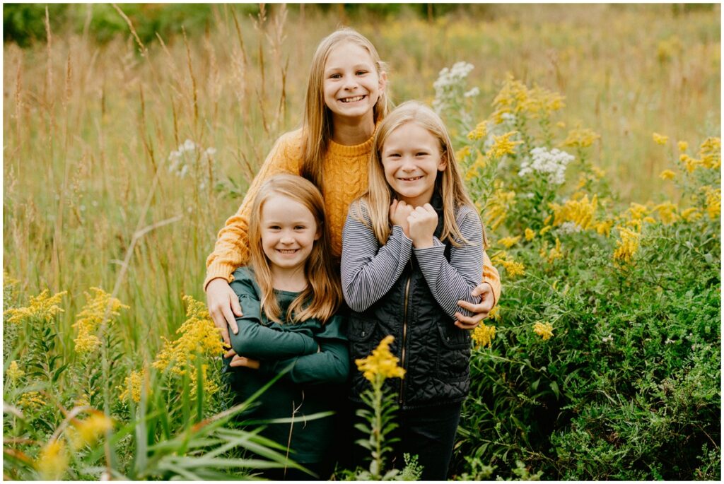 three sisters smiling in a field