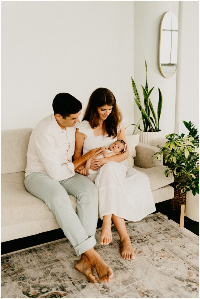 new parents with newborn baby on couch