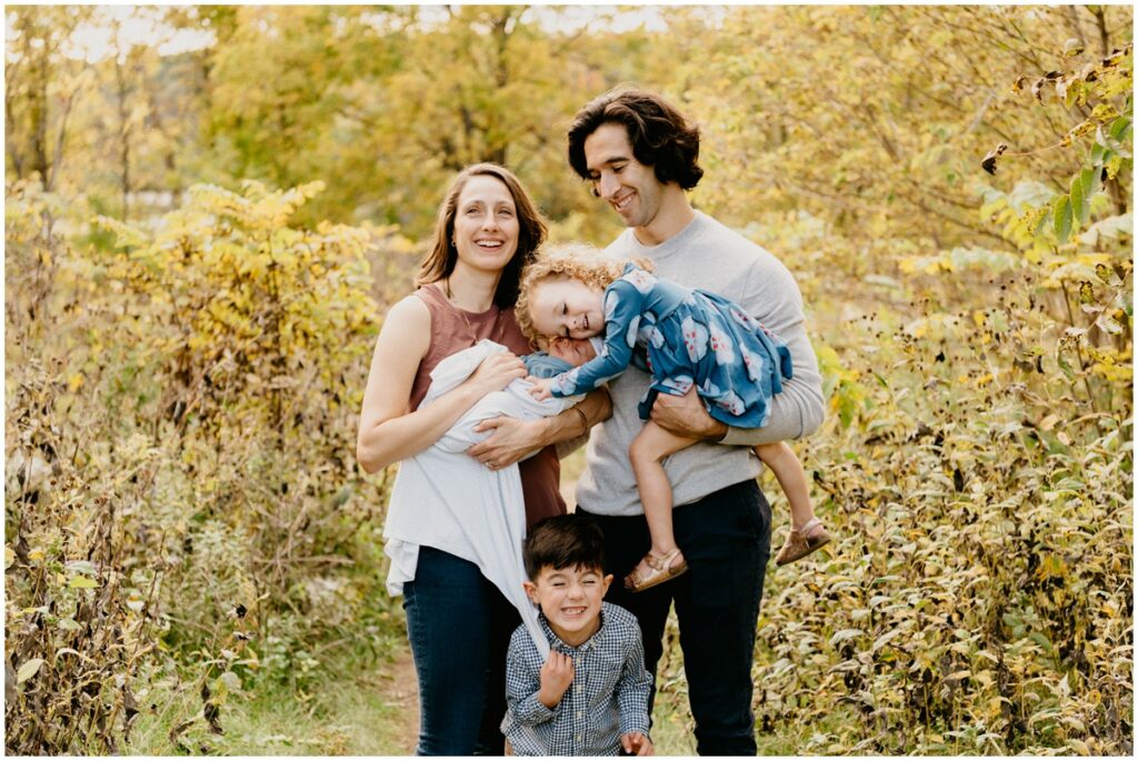 family smiling at a park in the fall