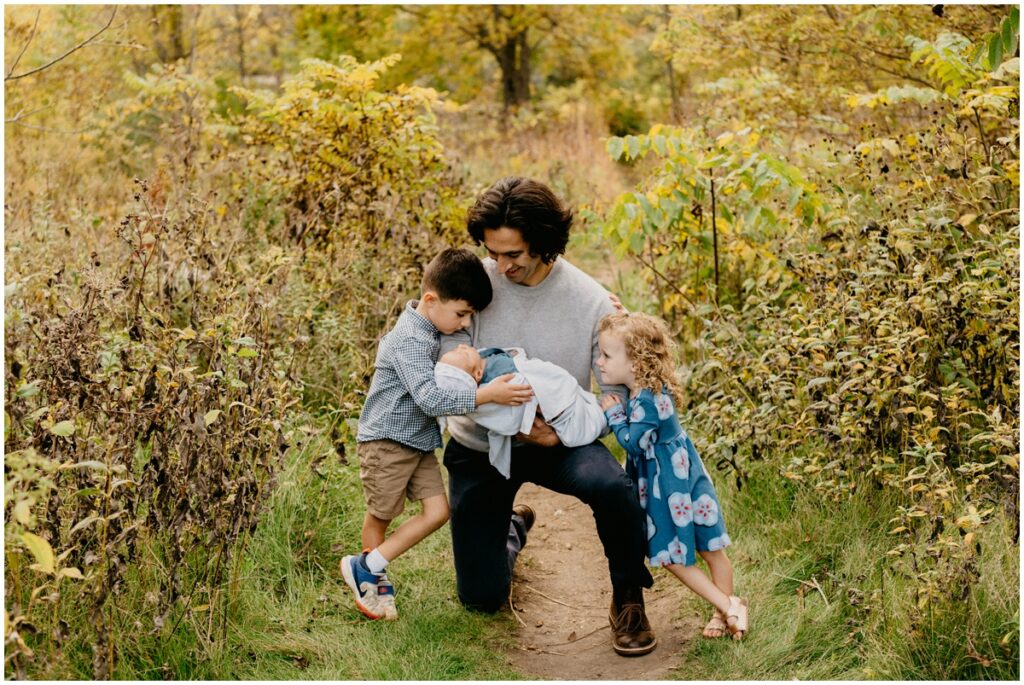 kids hugging dad with infant