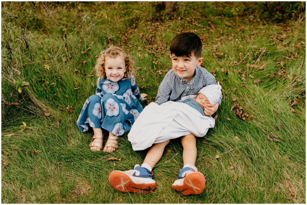 three kids smiling holding baby