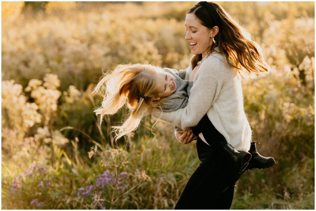 mom dancing with daughter at park in the fall