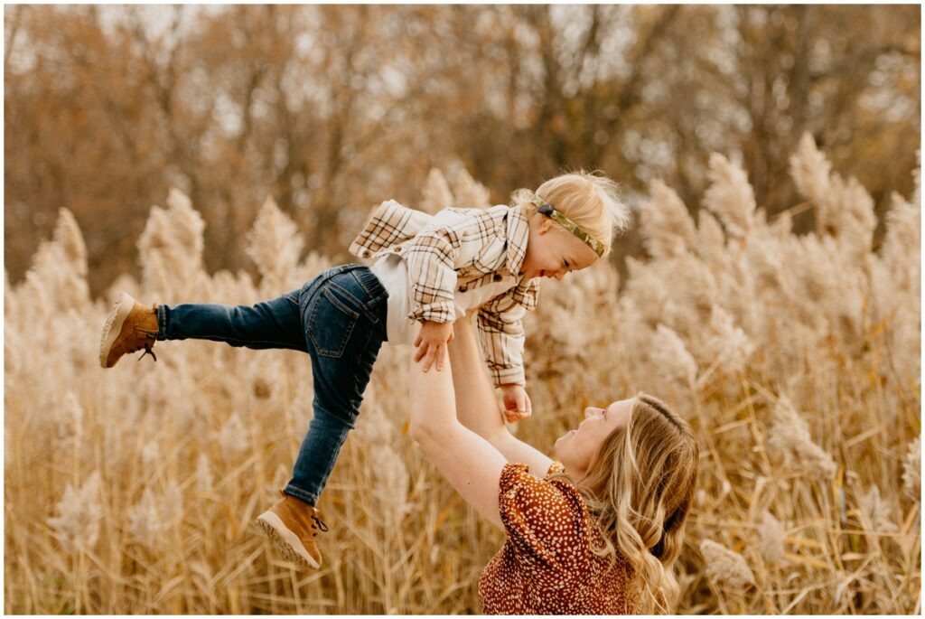 mom holding her child in the air smiling
