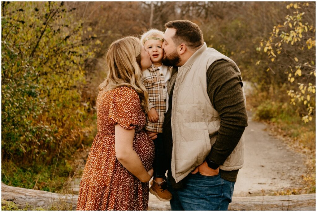 family kissing boy at a park