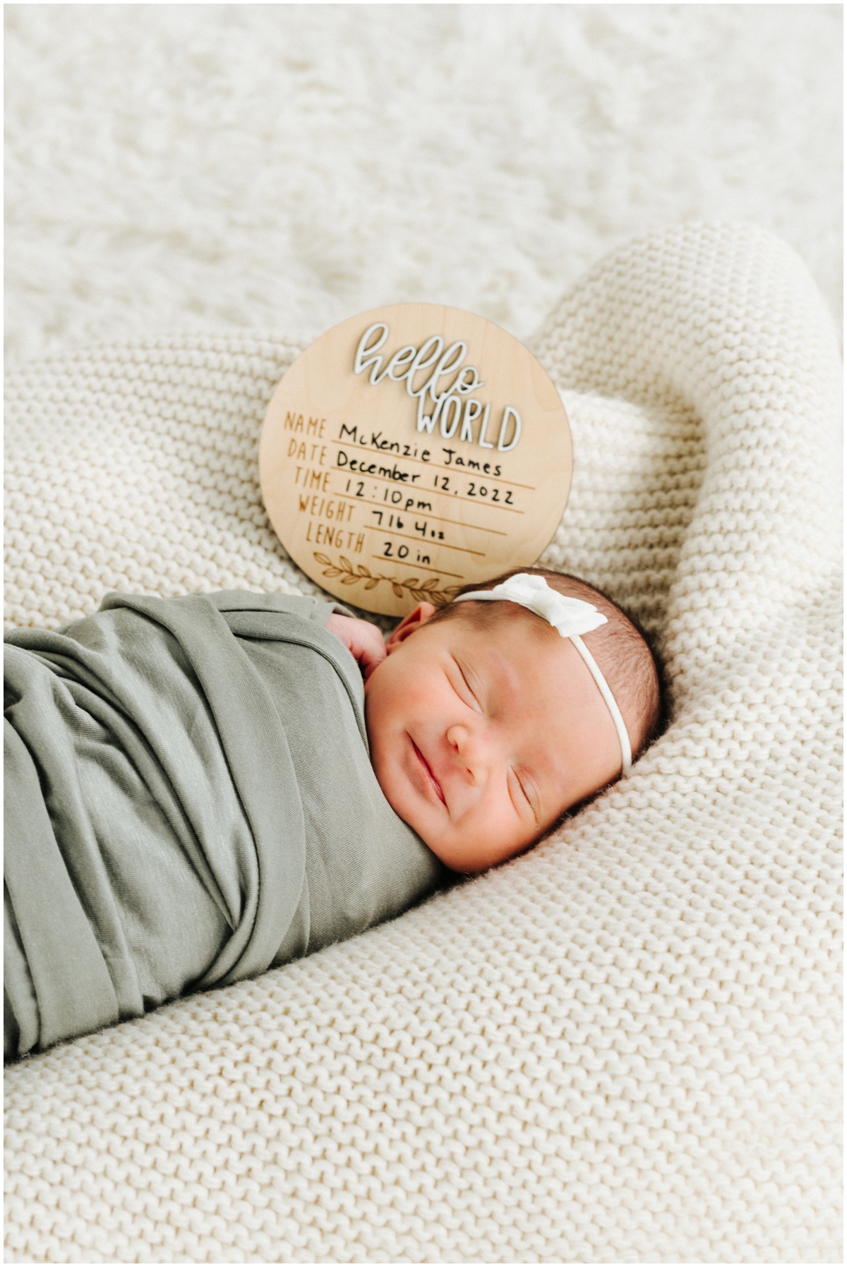 smiling newborn baby with name plate