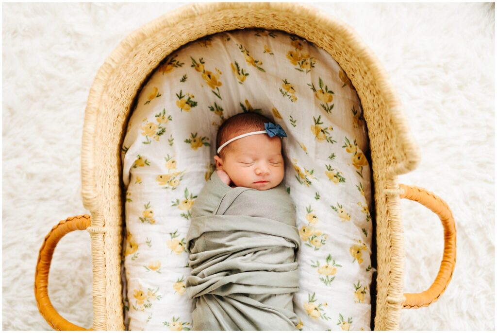 baby girl in a sage colored swaddle sleeping in basket