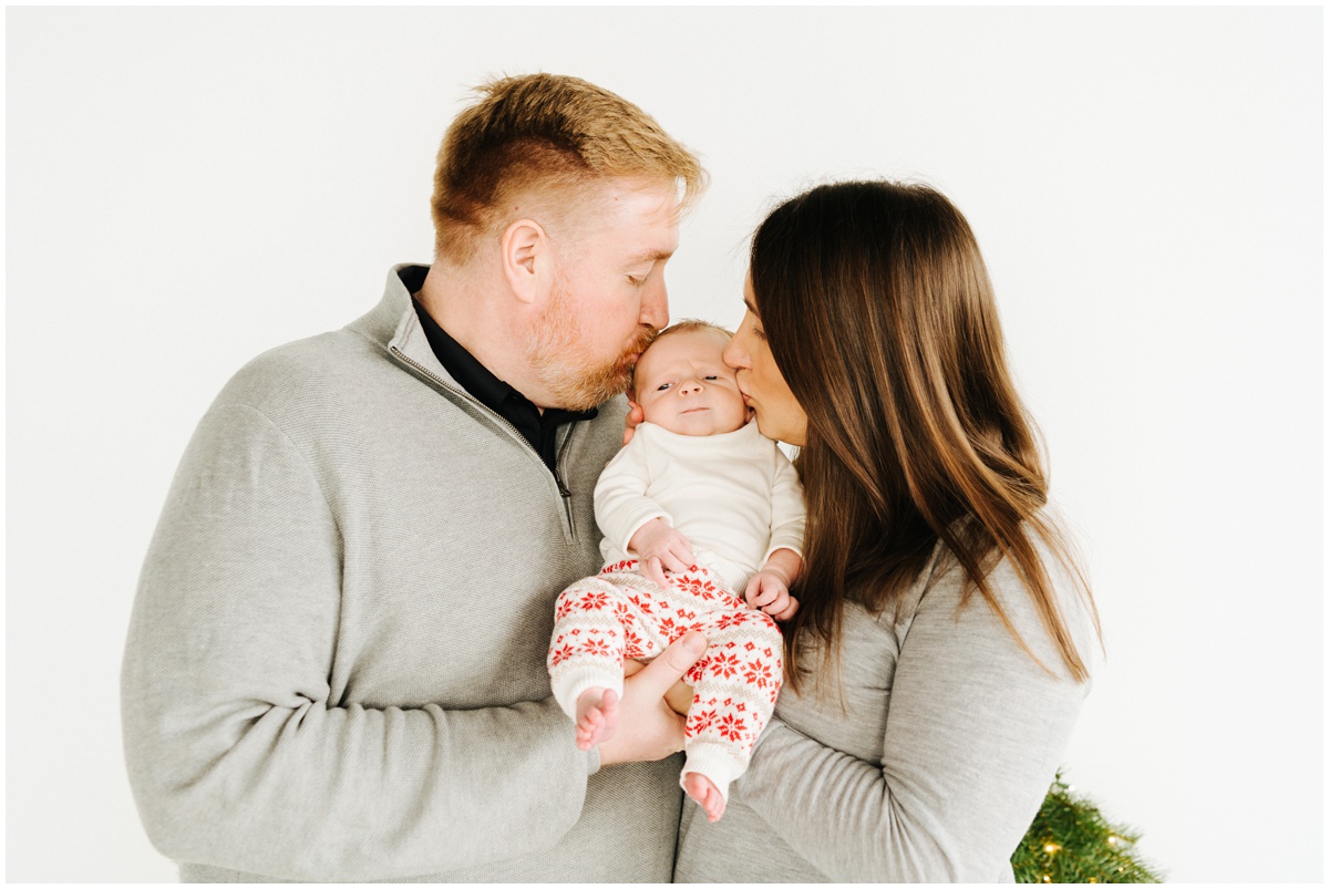 mom and dad kissing newborn baby boy