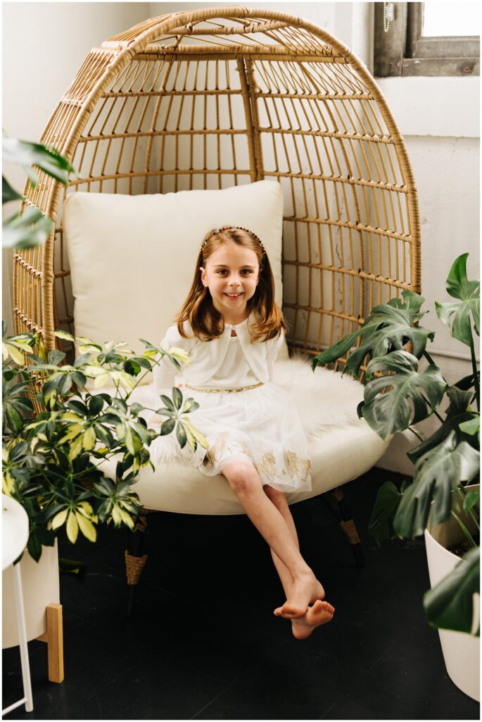 little girl in a boho chair with plants around it