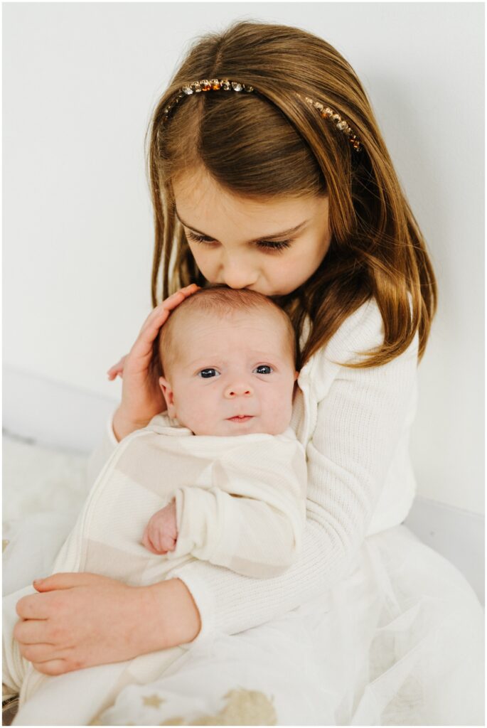 big sister kissing newborn baby sister