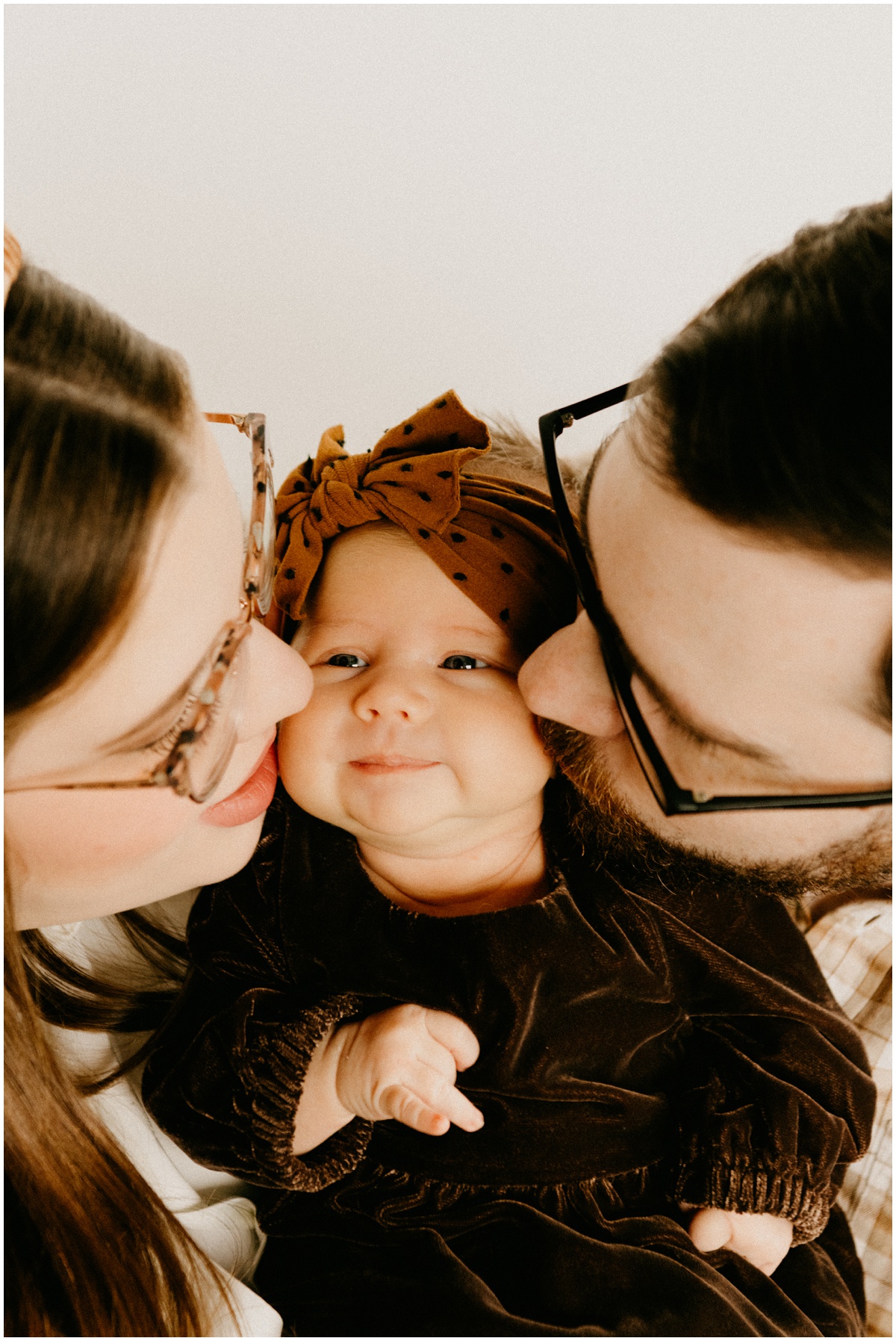 parents kissing baby girl on the cheeks