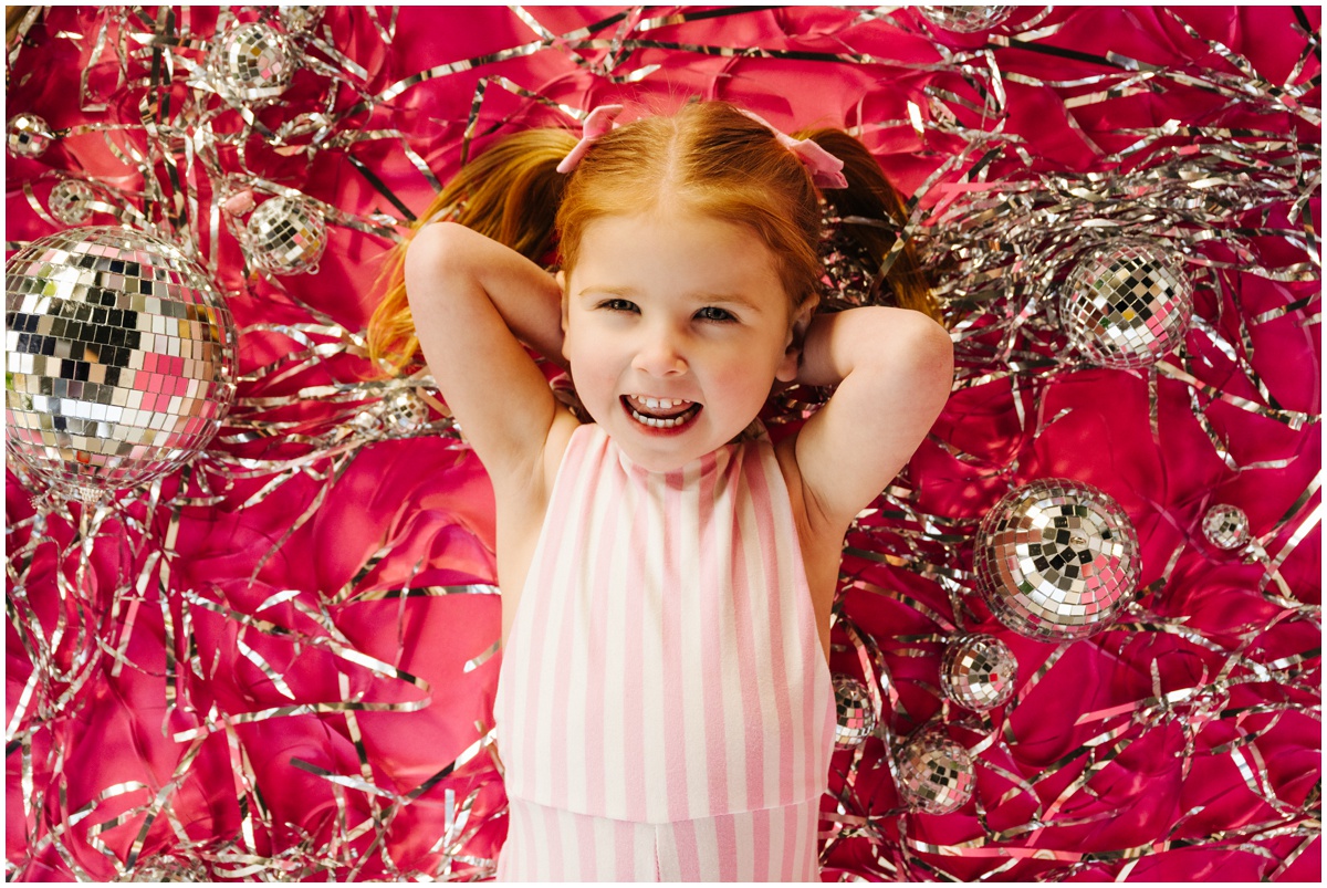 girl with disco balls on pink backdrop