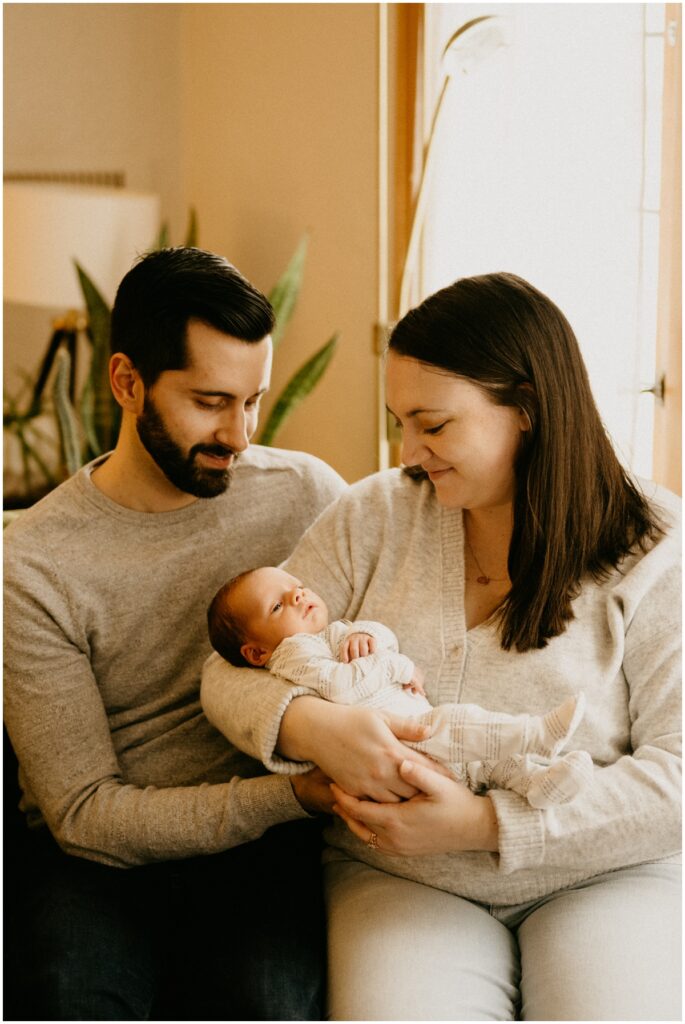 mom and dad holding little infant smiling