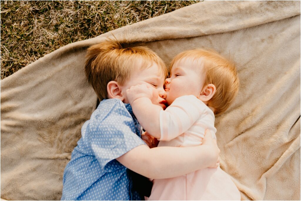 brother sister hugging at park on blanket