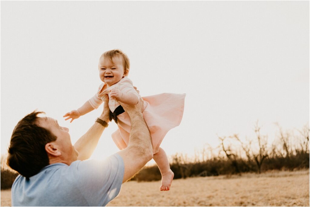 tossing little girl up into the air at park