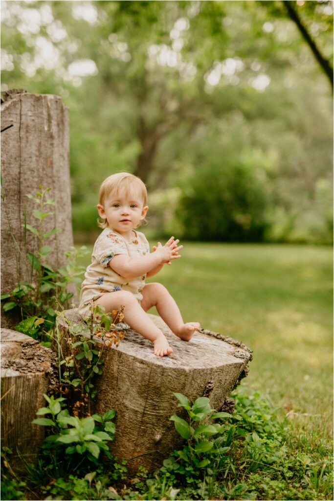 little girl sitting on a stump outside