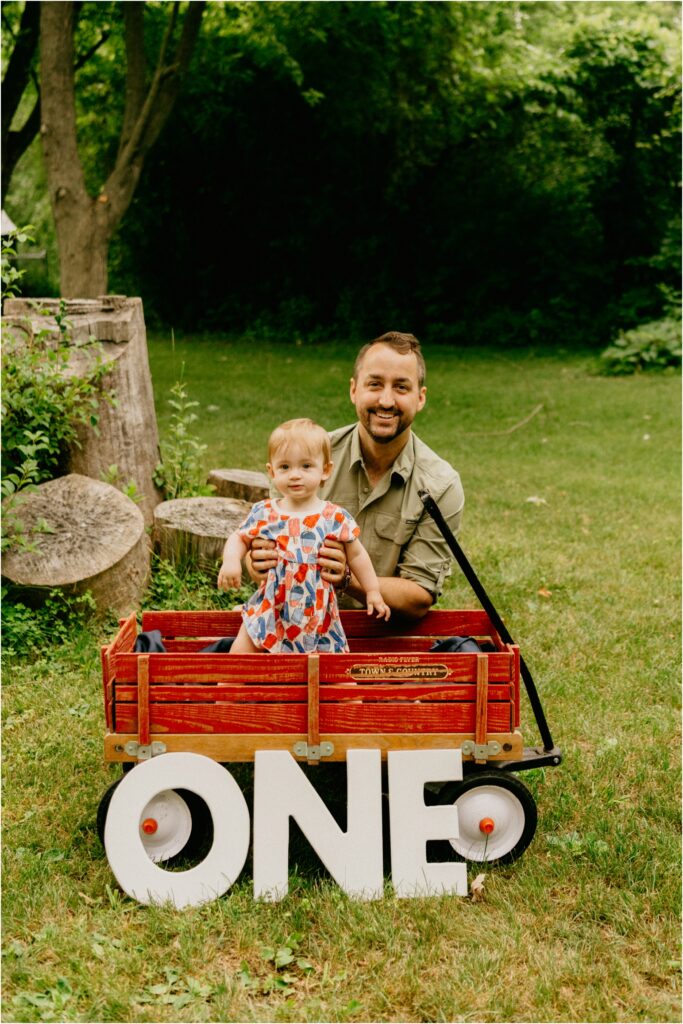 dad with daughter standing in a red wagon