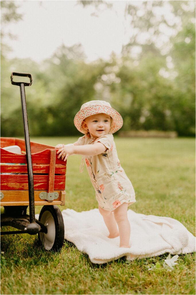 little girl standing by red wagon