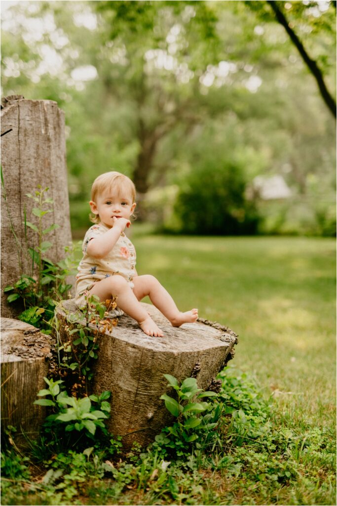 baby girl sitting on a stump
