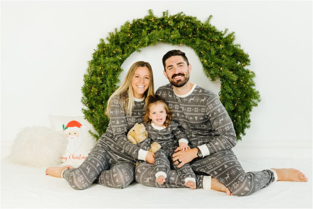 smiling holiday family photo in front of wreath