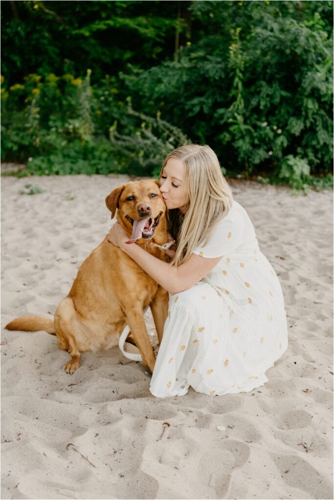 a woman kissing her dog at the beach