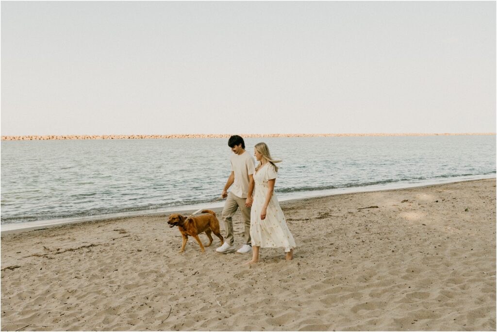 a couple walking down the beach with their dog