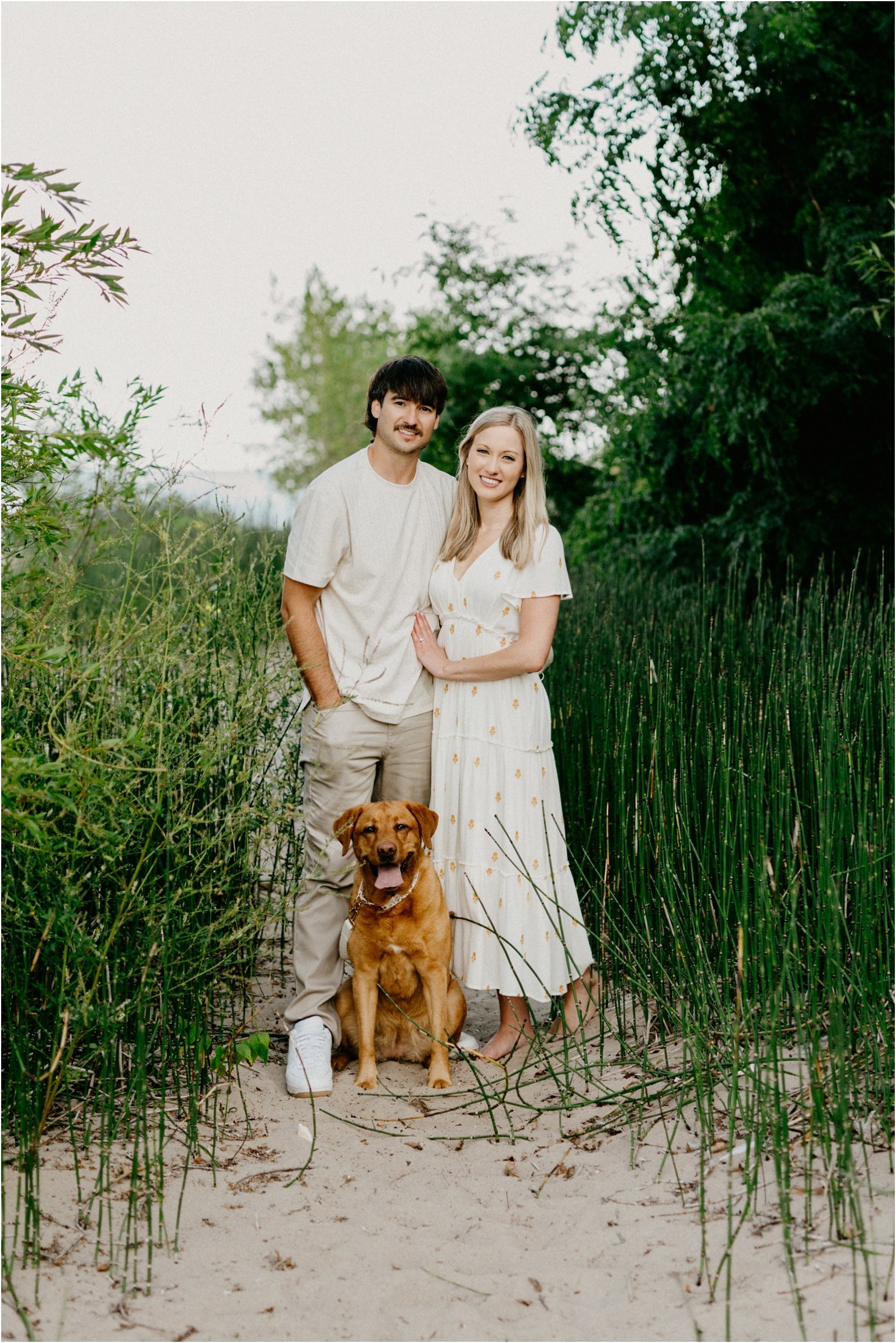 a couple with their dog posing at the beach