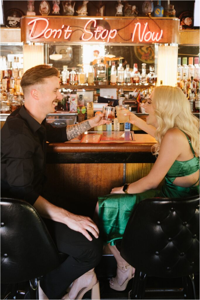 engagement photo of a couple in a bar with drinks