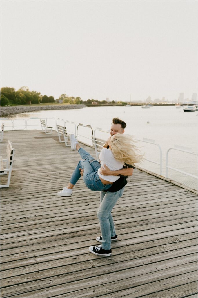 a couple dancing on a dock by the lake