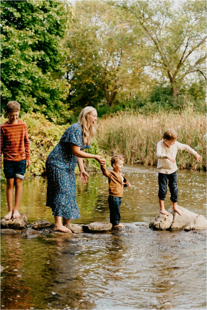 kids in a river on rocks with their mom