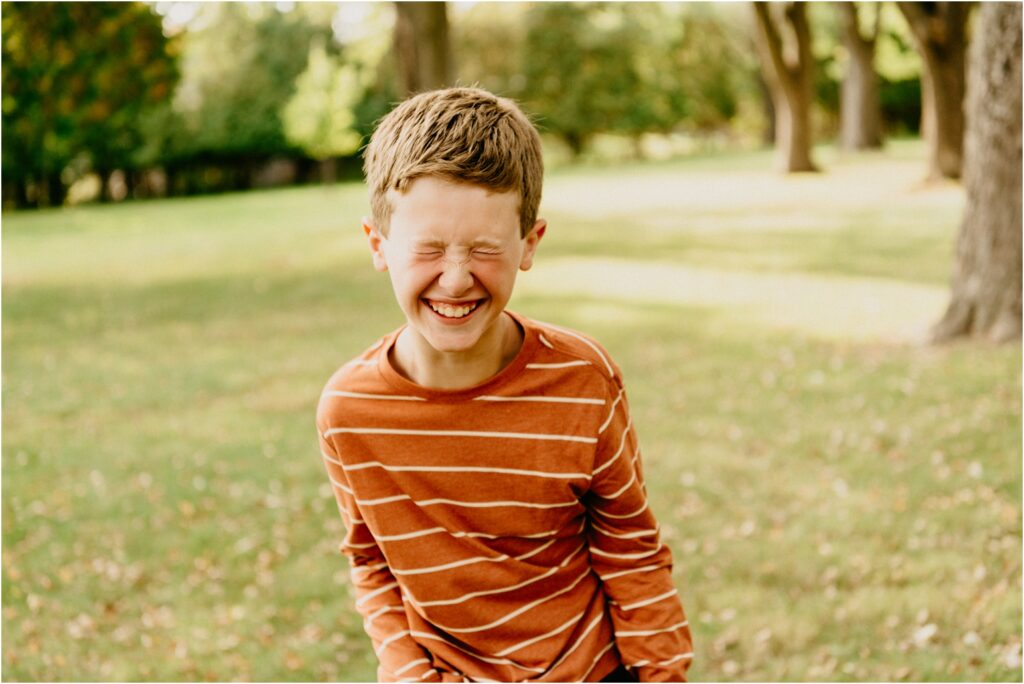 boy in orange shirt laughing at park