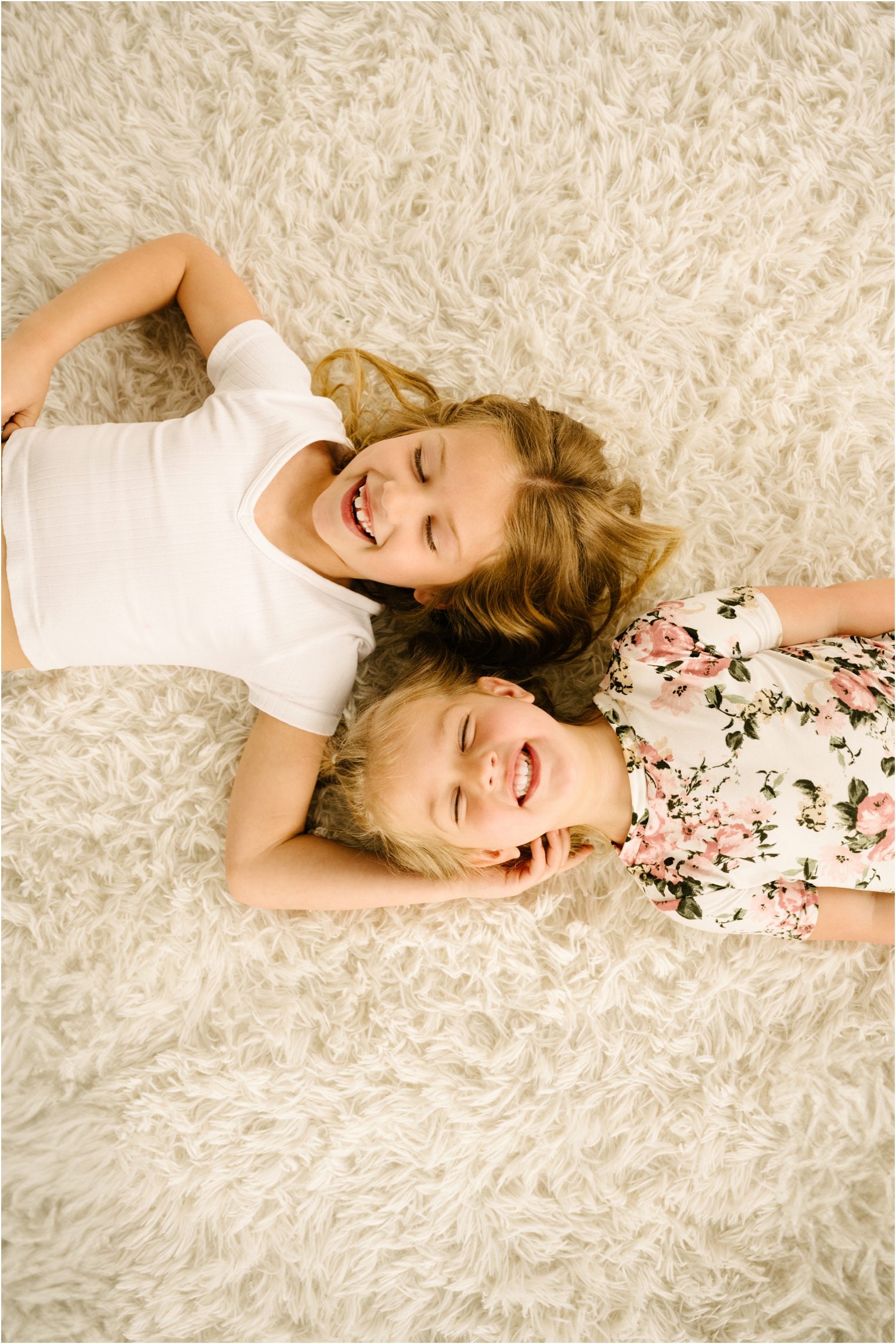 two sisters laying on backs smiling and laughing