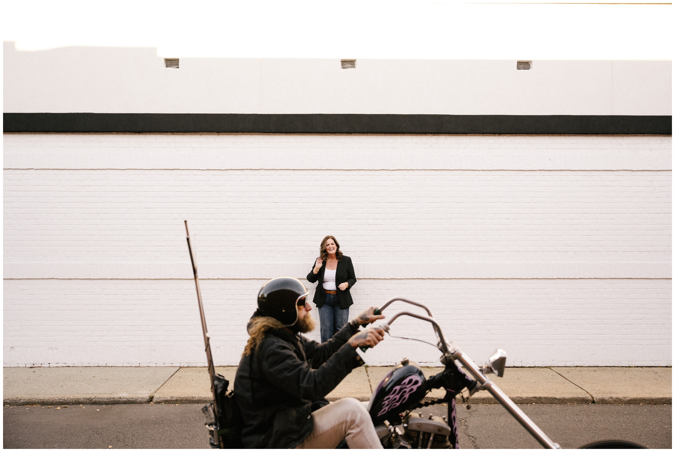 woman smiling against wall with motorcycle in the foreground